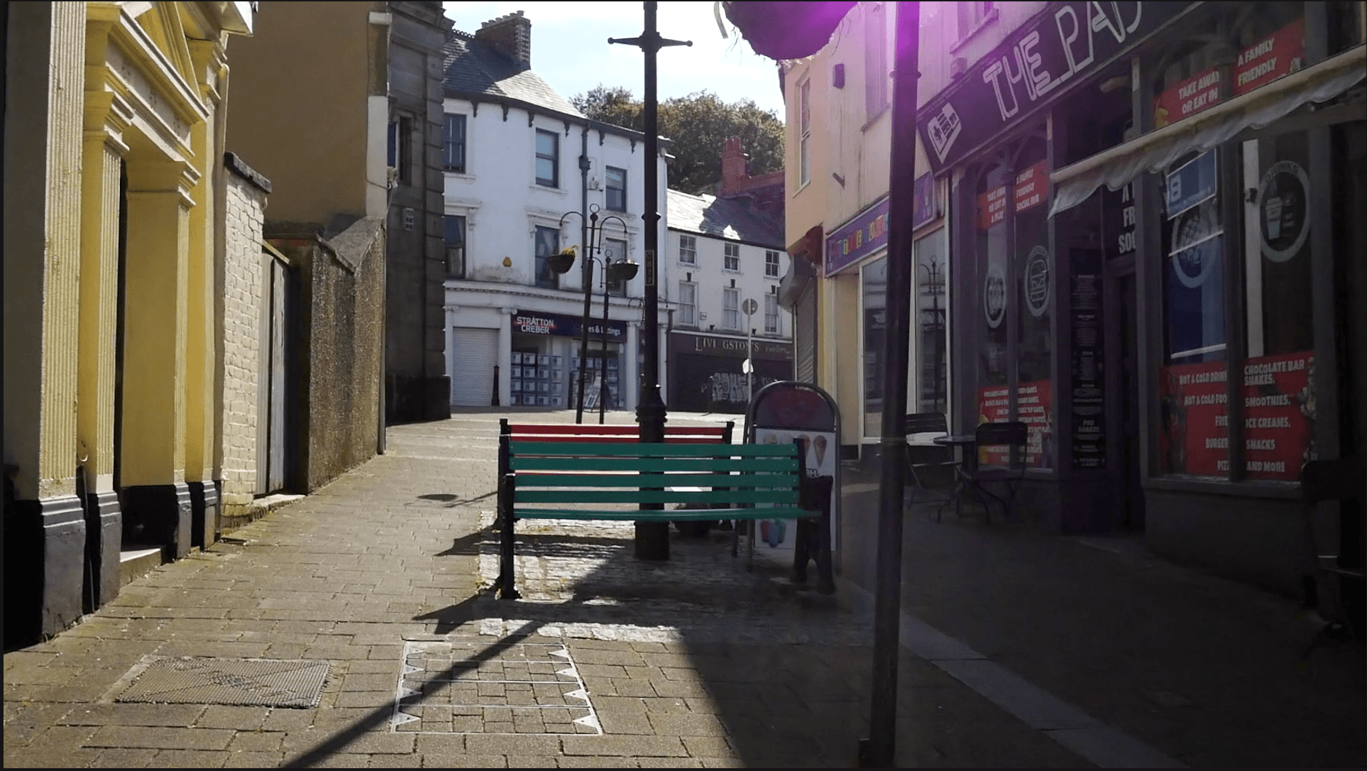 A view looking up Honey Street in Bodmin with small shops and benches