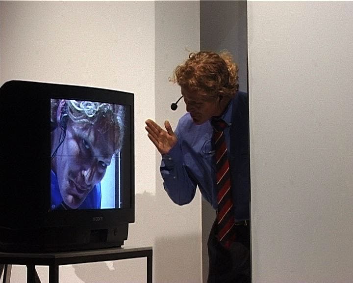 Henning gesturing to a TV with his own face on it